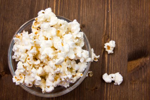 Popcorn in bowl on wooden table seen from above