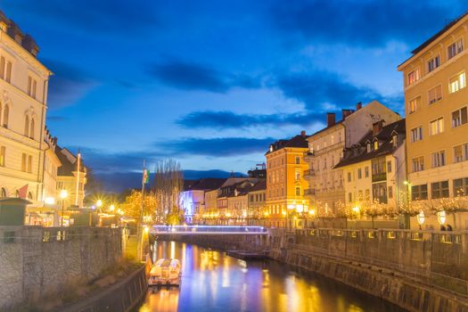 View of lively river Ljubljanica bank with new bridge in old city center decorated with Christmas lights. Ljubljana, Slovenia, Europe. Shot at dusk.
