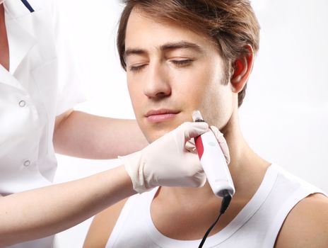 Handsome man during microdermabrasion treatment in beauty salon