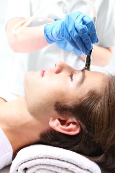 Handsome man during microdermabrasion treatment in beauty salon