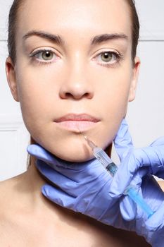 The face of a beautiful woman during the procedure of modeling the mouth, injecting