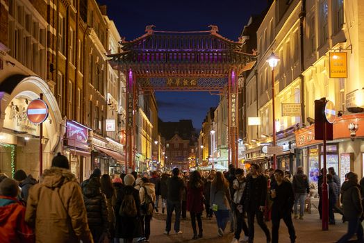 LONDON, UK - JANUARY 02: Pedestrians walking through traditional Chinese portal in  Gerrard Street at night, lined with illuminated shop banners, in Chinatown. January 02, 2015 in London.