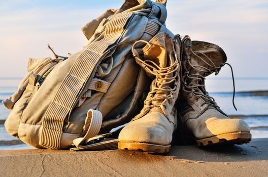 Yellow boots with a shoelaces and backpack on a sandy beach