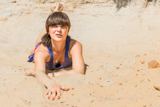 beautiful brunette lying on the warm sand on the beach