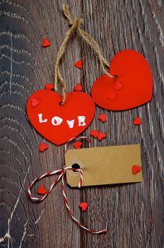 Two Red Hearts with Word Love, Blank Gift Card and Small Hearts closeup on Dark Wooden background