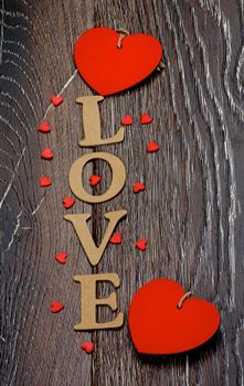Cardboard Word Love and Two Red Hearts closeup on Dark Wooden background