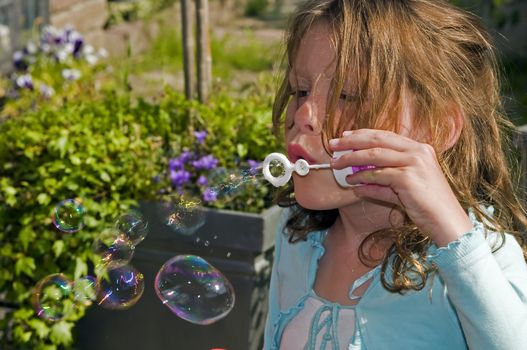 blond causcasian girl blowing soap bubbles