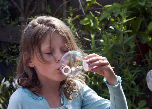blond causcasian girl blowing soap bubbles