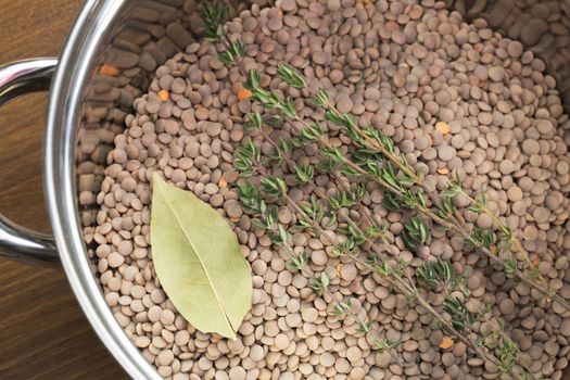 Lentils, thyme and bay leaf in pot, ready for cooking.