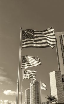 Waving american flags against modern buildings and blue sky.