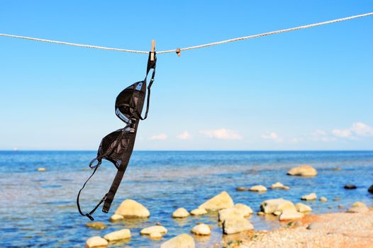 Female brassiere hanging on a rope on a seashore