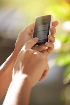 Hands of woman with smartphone in the garden