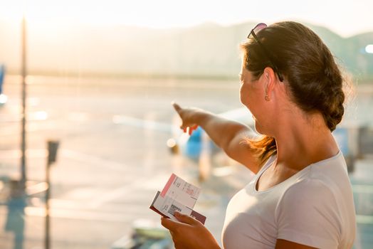 beautiful brunette showing a plane at the airport