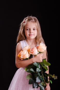 Portrait of a five year old girl with a bouquet of flowers on a black background