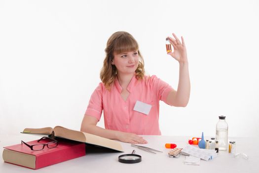 Pharmacist sitting at the table reading a thick handbook of medicines