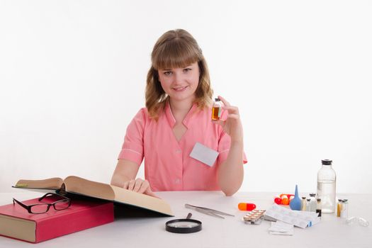 Pharmacist sitting at the table reading a thick handbook of medicines