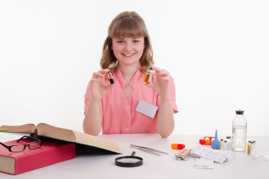 Pharmacist sitting at the table reading a thick handbook of medicines