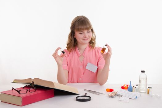 Pharmacist sitting at the table reading a thick handbook of medicines