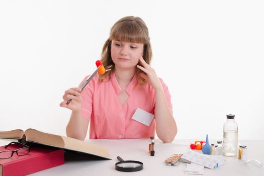 Pharmacist sitting at the table reading a thick handbook of medicines