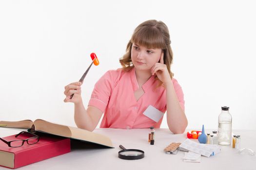 Pharmacist sitting at the table reading a thick handbook of medicines