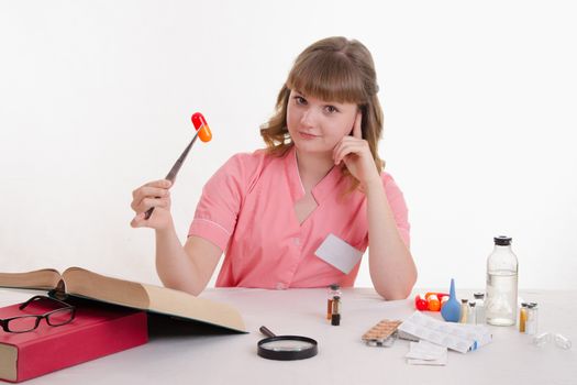 Pharmacist sitting at the table reading a thick handbook of medicines