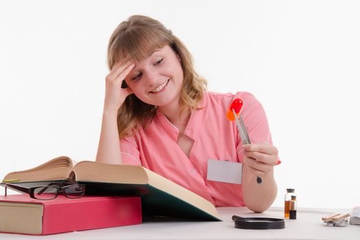 Pharmacist sitting at the table reading a thick handbook of medicines