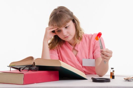 Pharmacist sitting at the table reading a thick handbook of medicines