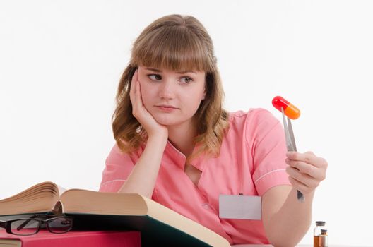 Pharmacist sitting at the table reading a thick handbook of medicines