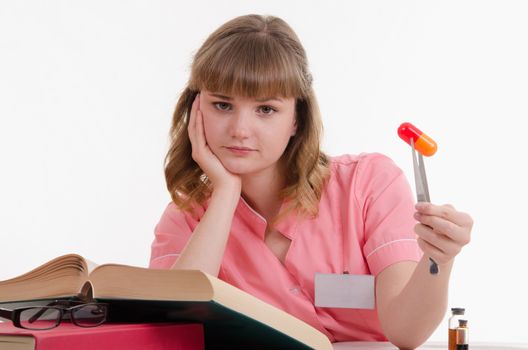 Pharmacist sitting at the table reading a thick handbook of medicines