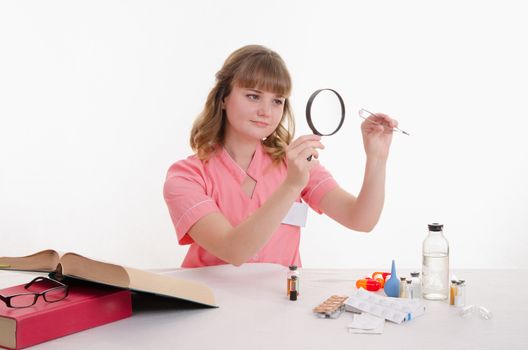 Pharmacist sitting at the table reading a thick handbook of medicines