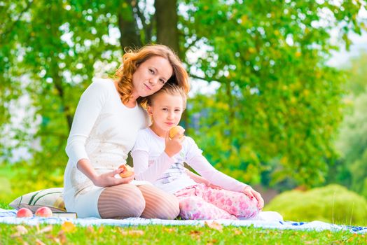 happy family on a picnic snack apples in the park