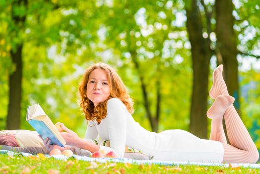 romantic girl with a good book and a delicious apple in the park