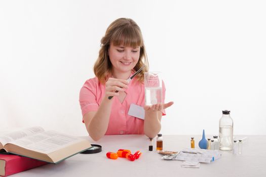 Pharmacist sitting at the table reading a thick handbook of medicines