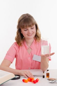 Pharmacist sitting at the table reading a thick handbook of medicines