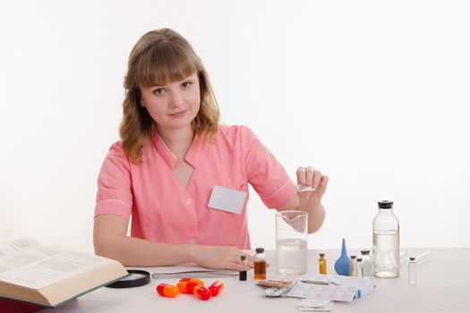 Pharmacist sitting at the table reading a thick handbook of medicines