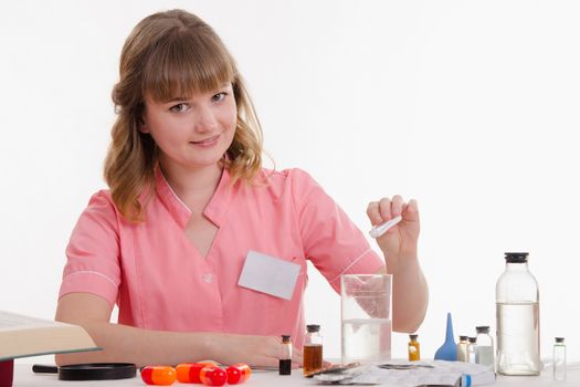 Pharmacist sitting at the table reading a thick handbook of medicines