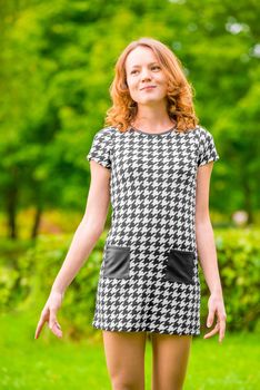 happy girl in a dress on a background of green park