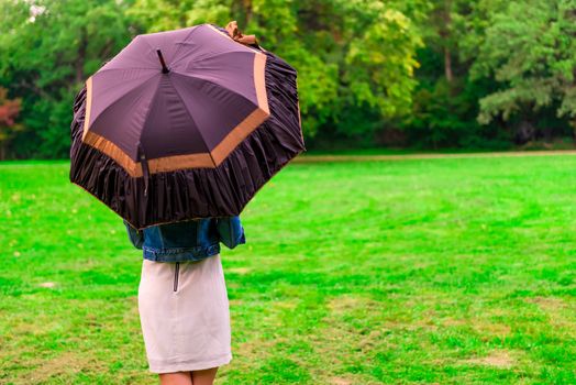 woman standing in the meadow under the open umbrella