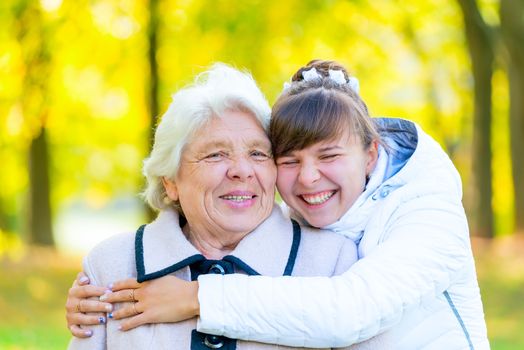 granddaughter and grandmother embracing in autumn park