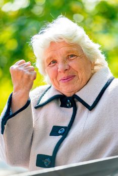 gray-haired old lady shows a fist in the park