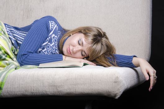 The girl was reading a book lying on the couch. In the process of reading the girl fell asleep