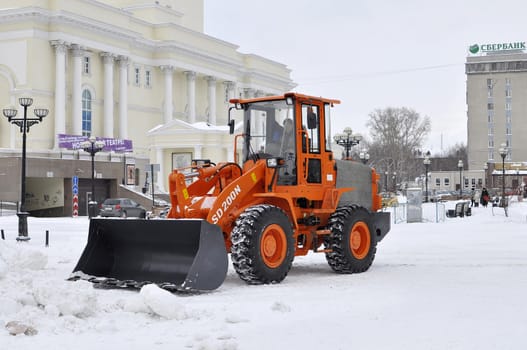 The bulldozer occupied with snow cleaning is on the square near the Tyumen drama theater in the city of Tyumen