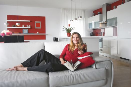 young beautiful woman sitting on soffa in modern kitchen interior