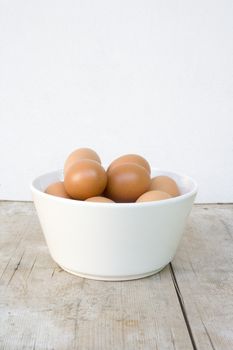 white bowl with brown eggs standing on wooden board