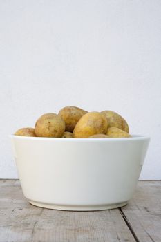 white bowl with potatoes on wooden board