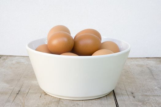 white bowl with brown eggs standing on wooden board