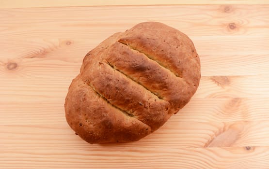 Freshly baked loaf of multi seed malted bread on a wooden table