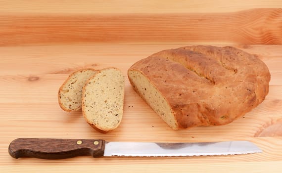 Bread knife with slices of bread cut from a seeded loaf of bread