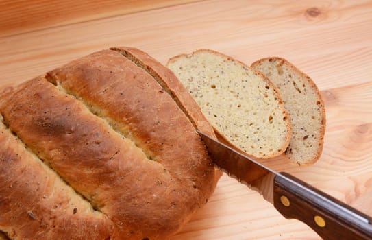 Cutting slices of bread from a freshly baked loaf on a wooden table