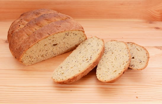 Three slices of fresh bread next to a new loaf of multi seed bread on a wooden surface